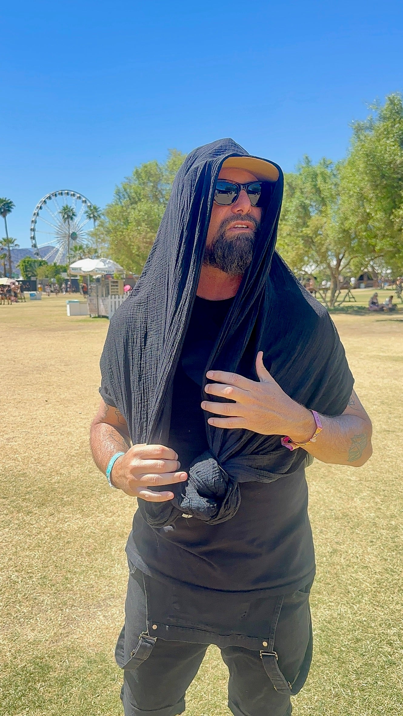 BLACK SUNCHILD SLING BEING USED BY FOUNDER AND MUSICIAN AS A COOLING SHADE COVER WITH ADDED WATER FOR COOLING FOM THE SUN AT COACHELLA MUSIC FESTIVAL